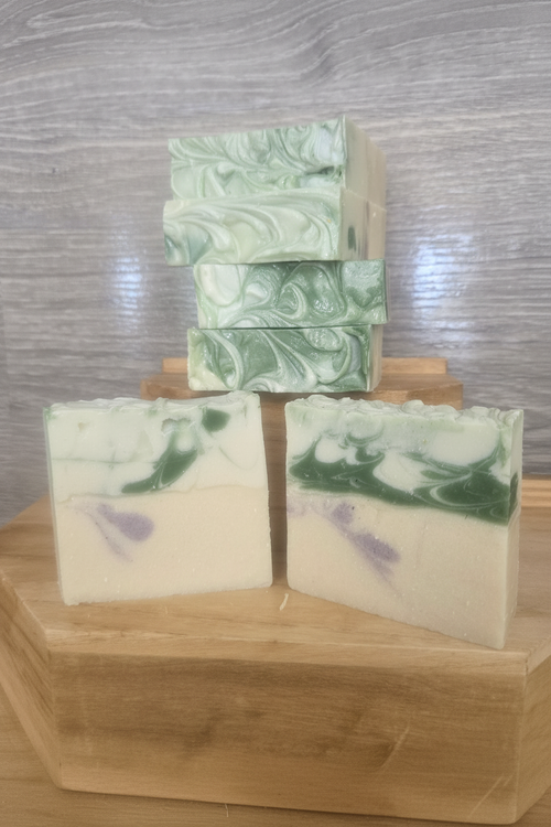 Handcrafted goat milk honey oat soap bars with green and white swirl on wooden blocks - enhanced
